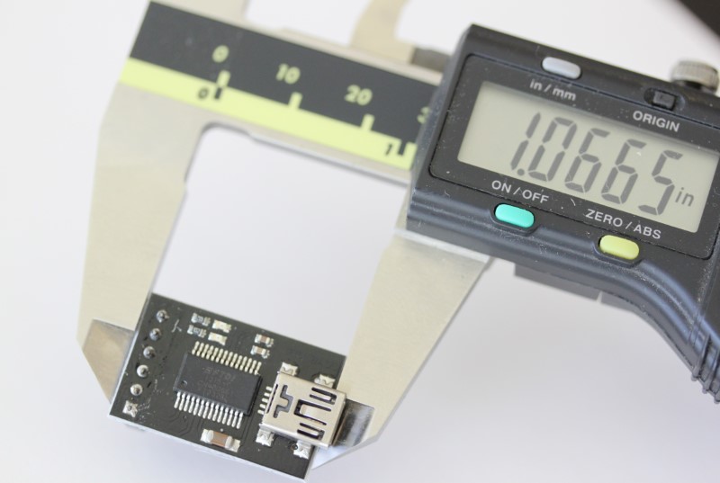 USB to serial converter shown with caliper. The measurement reads 1.0665 inches.