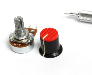 This image depicts a potentiometer and a small knob shown side by side with a pencil tip for scale.